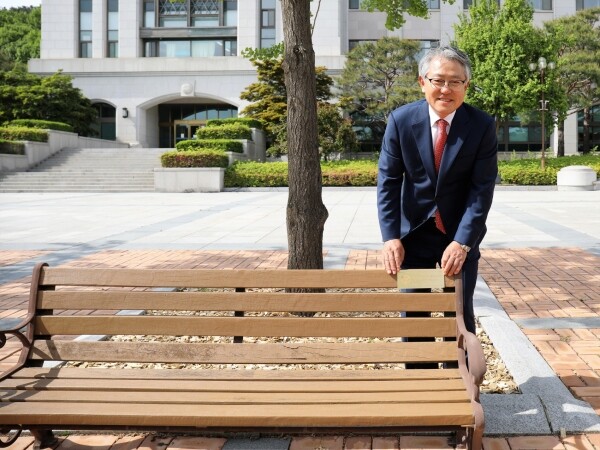 배선길 선문대 총동문회장이 자신의 명패가 부착된 대학본관 앞 야외 벤치에 서 기념촬영하고 있다. 배 회장은 야외 벤치 2호 기부자다. 사진=선문대 제공