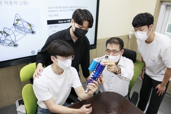 ‘백년 소공인’ 조성기 오성스프링 대표(가운데)가 산기대생들에게 자작자동차에 장착되는 스프링 부품에 대한 조언을 하고 있다. 사진=산기대 제공