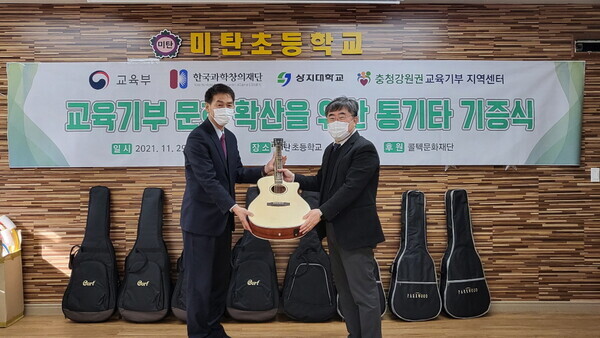 이제원(오른쪽) 상지대 충청강원권 교육기부 지역센터장이 평창 미탄초등학교에 통기타를 전달하고 있다. 사진=상지대 제공 