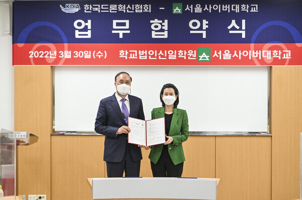 박주성(왼쪽) 한국드론혁신협회 부회장과 강인 서울사이버대 총장이 업무협약을 체결한 뒤 협약서를 펼쳐보이고 있다. 사진=서울사이버대 제공