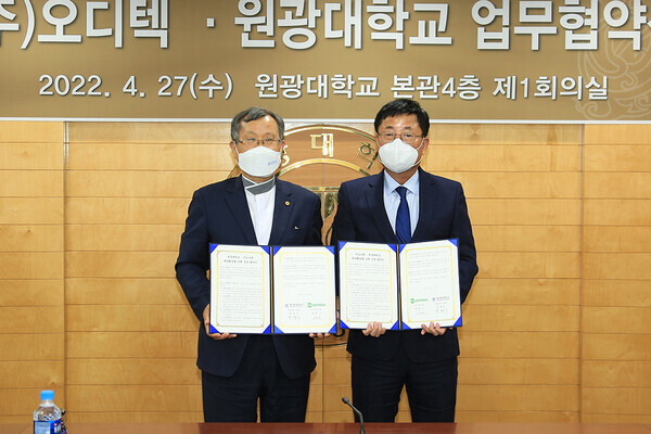 박맹수(왼쪽) 원광대 총장과 최봉민 오디텍 반도체분야 대표가 업무협약을 체결한 후 협약서를 펼쳐보이고 있다. 사진=원광대 제공